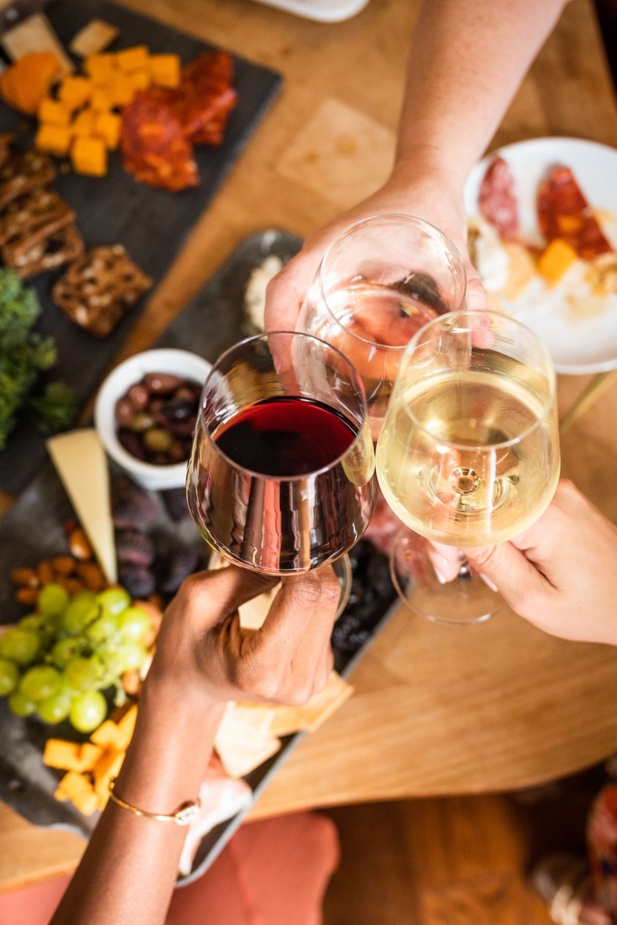 Guests toasting with red and white wine over a shared board