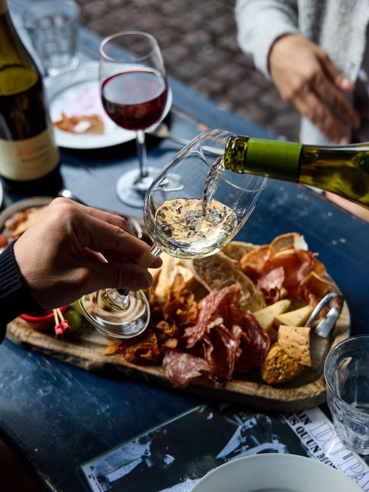 A charcuterie board with red wine being enjoyed by guests