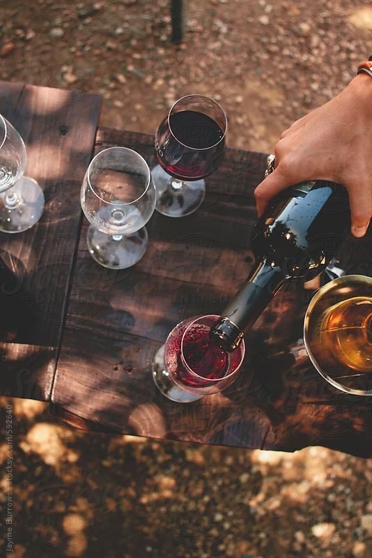 Red wine poured outdoors among a gathering of glasses
