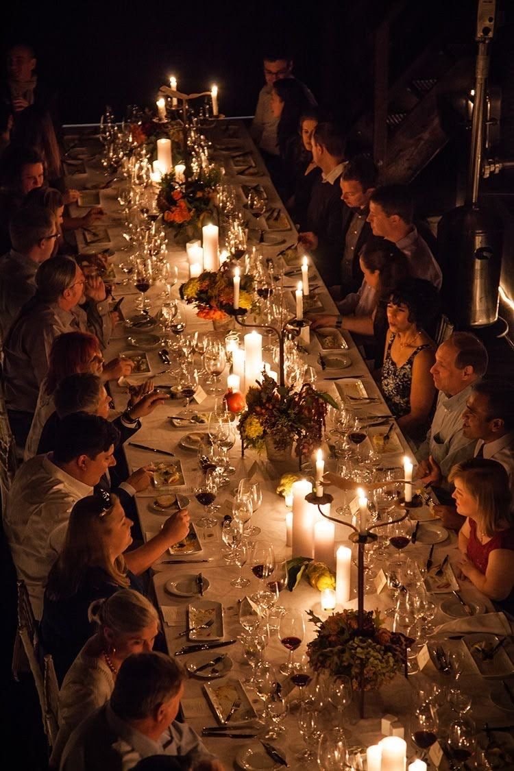 A long candlelit dinner table seen from above, set for many guests